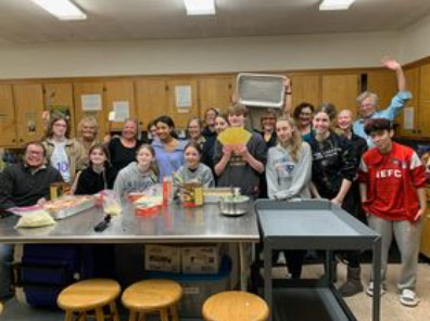 Coming of Age (COA) Program - A group of youth and adults in a kitchen prepare to make lasagna.