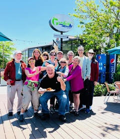 A group of adults pose happily in front of a vegan restaurant.