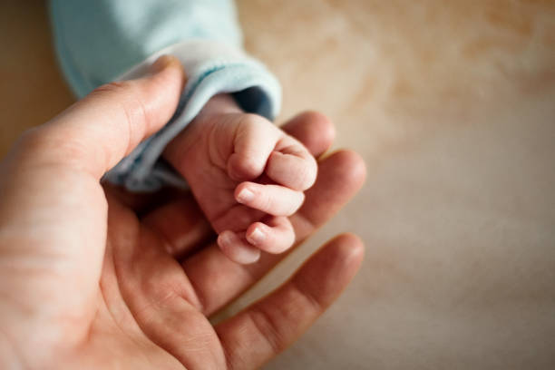 Close-up from a father's hand, holding his newborn's hand, giving him love, trust and security.