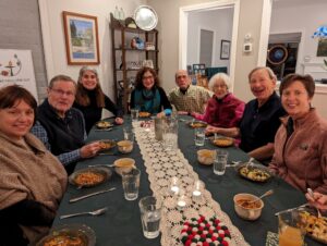 A group of adults sit around a table eating delicious plant-based food together.