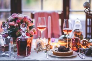 An elegant table with plates, wine glasses, a decanter, and a floral centerpiece.