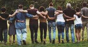 a group of people stand in a line with their backs to the camera and their arms around one anothers' waists and shoulders