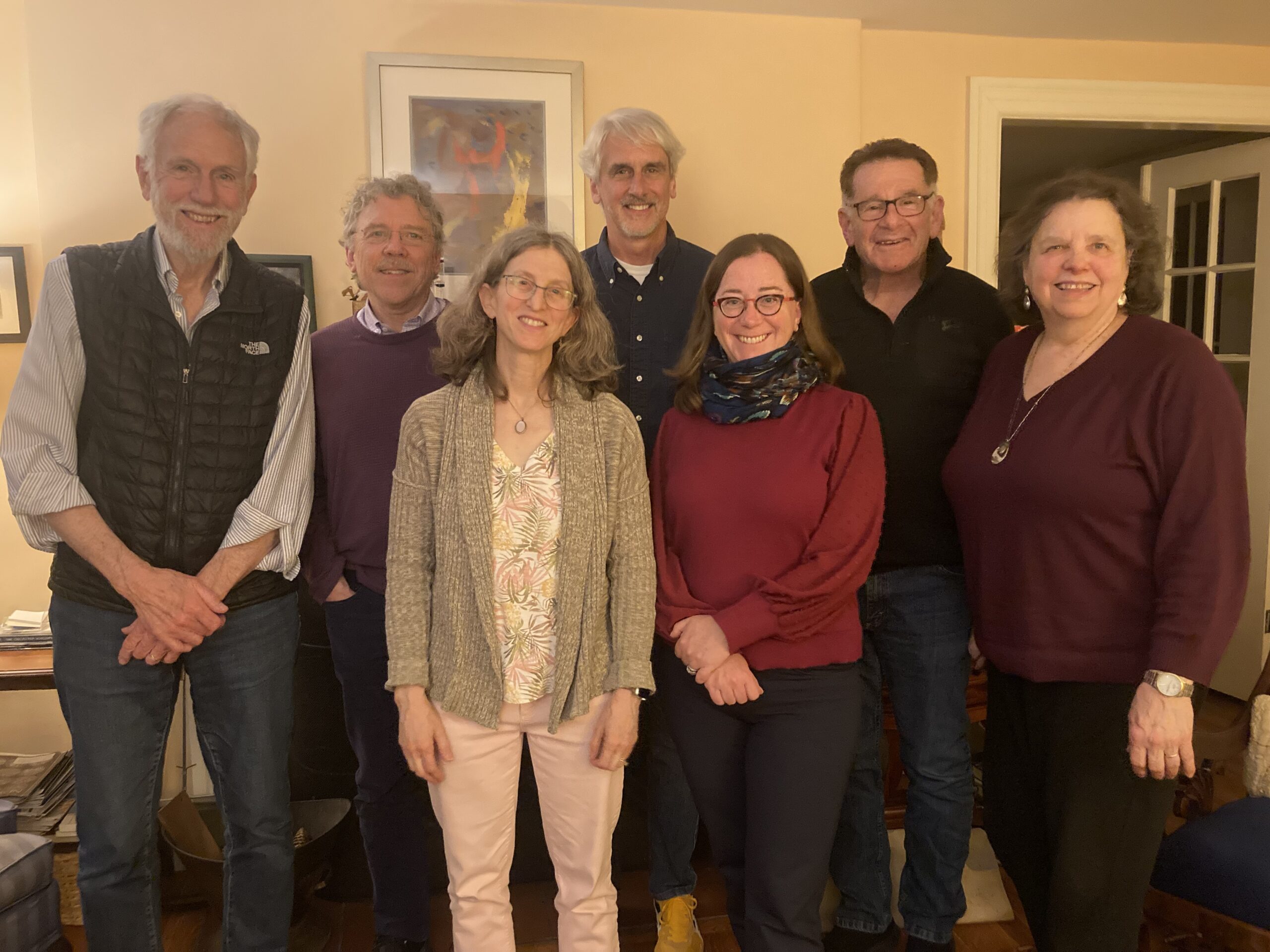 A group photo of our Lay Ministers, from left to right: Jud Leonard, a tall man with gray hair and beard wearing a striped button-up shirt, a black quilted vest, and blue jeans; Jay Flynn, a man with gray hair and moustache wearing glasses, a light purple button-up shirt, dark purple sweater, and navy pants; Ellen Metzger, a woman with shoulder-length gray hair wearing glasses, a pink and green tropical print shirt, a variegated beige cardigan sweater, and pink pants; Gordon Moriarty, a tall man with gray hair and beard, wearing a navy button-up shirt over a white T-shirt, blue jeans, and bright yellow sneakers; Christine Lookner, a woman with shoulder-length brown hair wearing glasses, a red long-sleeved shirt, a dark-blue printed scarf, and dark blue slacks; Cris Goldsmith, a man with brown hair wearing glasses, a black fleece jacket, and blue jeans; and Nancy Mattei, a woman with chin-length brown hair wearing drop earrings, a long silver pendant, a purple v-neck sweater, and black pants.