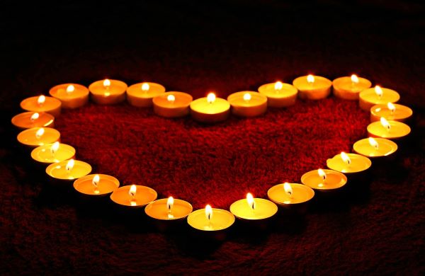 Lit tea light candles form a heart shape atop a red rug